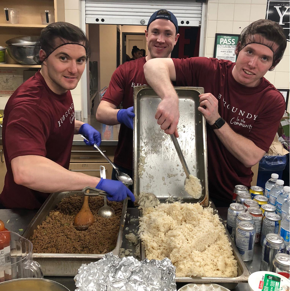 Three BAM volunteers serving food at a kitchen
