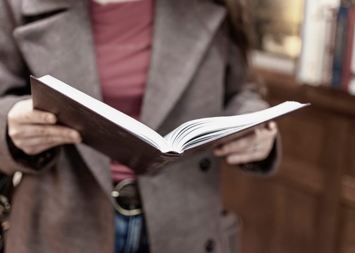 community-literacy Woman with book open in her hands, in a bookstore